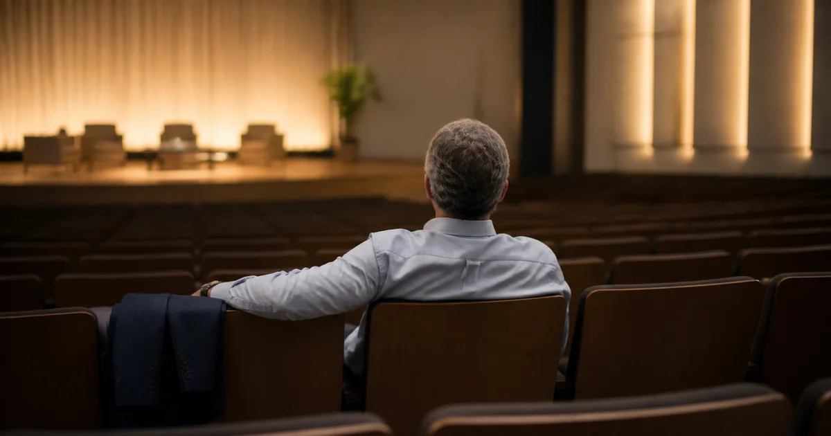 Male leader sitting alone in an auditorium after a presentation